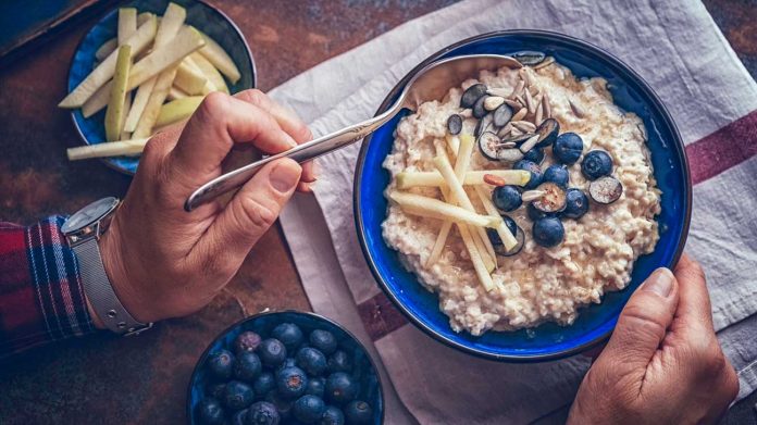 man-eating-oatmeal-blueberries-apples-1296x728